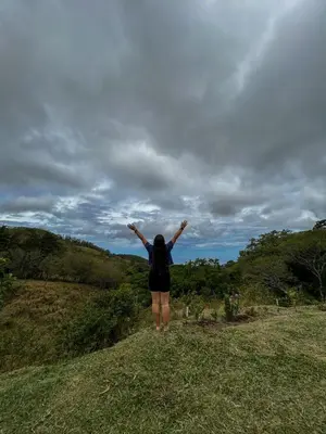 a woman standing on a hill with her arms in the air at Casa Urraca, Magnífica Vista al Océano Pacífico in Monteverde Costa Rica