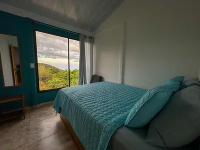 a bedroom with a bed and a large window at Casa Urraca, Magnífica Vista al Océano Pacífico in Monteverde Costa Rica