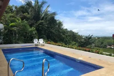 a swimming pool with chairs and a view of trees at Puesta del Sol in Quepos