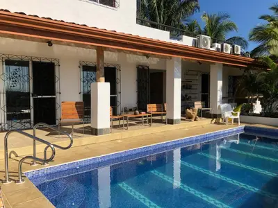 a house with a swimming pool in front of a house at Puesta del Sol in Quepos