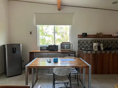 a kitchen with a wooden table and a refrigerator at Puesta del Sol in Quepos