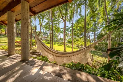 a hammock on the porch of a resort with palm trees at Casa Carmen in Potrero