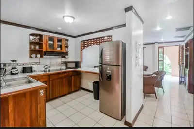 a kitchen with a stainless steel refrigerator and a table at Lovely Condo (8 people): Pools, Tennis Courts, BBQ in Manuel Antonio