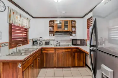 a kitchen with wooden cabinets and a black refrigerator at Lovely Condo (8 people): Pools, Tennis Courts, BBQ in Manuel Antonio