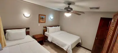a hotel room with two beds and a ceiling fan at Lovely Condo (8 people): Pools, Tennis Courts, BBQ in Manuel Antonio