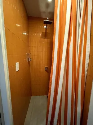 a bathroom with a shower with orange and white stripes at Nina´s - Juan Santamaria in Alajuela City