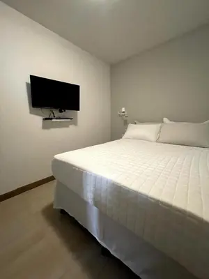 a bedroom with a white bed and a flat screen tv at Nina´s - Juan Santamaria in Alajuela City