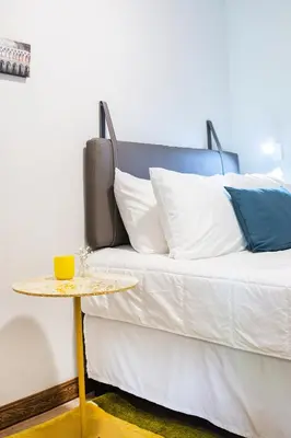 a bed with white pillows and a side table at Nina´s - Juan Santamaria in Alajuela City