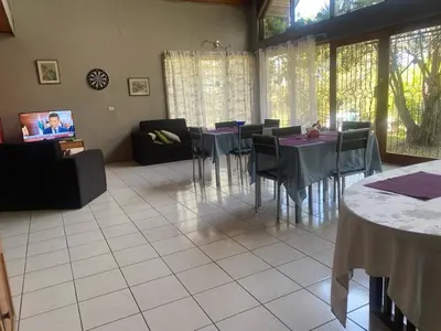 a dining room with tables and chairs and a tv at daBene - Bed & Breakfast in Alajuela City