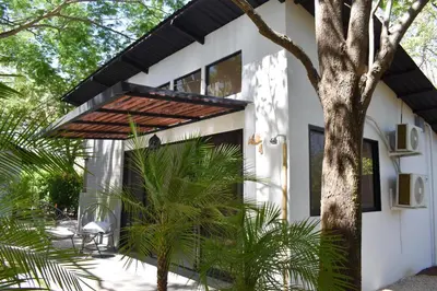 a white house with a black roof and a tree at Blue Window Boutique Villas Hotel in Playa Junquillal