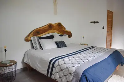 a bedroom with a large bed with a wooden headboard at Blue Window Boutique Villas Hotel in Playa Junquillal