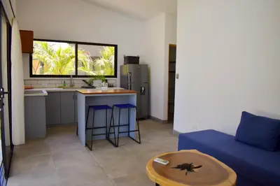 a kitchen and living room with a blue couch and a table at Blue Window Boutique Villas Hotel in Playa Junquillal