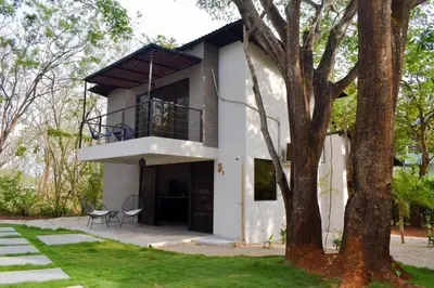 a white house with a balcony and a tree at Blue Window Boutique Villas Hotel in Playa Junquillal