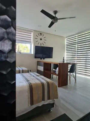 a bedroom with a bed and a desk and a clock at Cute Escazú Loft -Great view- in Escazu