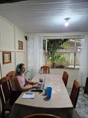 a woman sitting at a table with a laptop at Alpha Arenal Hostel in Fortuna