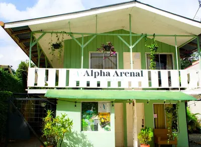 a green building with a sign that reads alpha american at Alpha Arenal Hostel in Fortuna