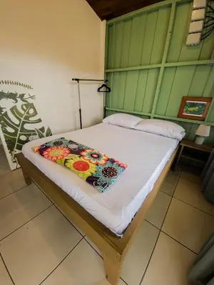a bed in a room with a white bedspread at Alpha Arenal Hostel in Fortuna