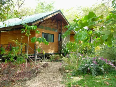 a wooden cabin with a garden in front of it at Nicoya Silvestre in Lepanto