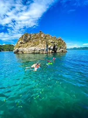 people swimming in the water near a small island at Nicoya Silvestre in Lepanto