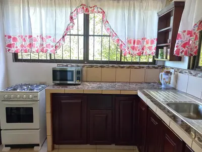 a kitchen with a stove and a sink and a window at Casa Montañas Nicoyanas in Juan Díaz