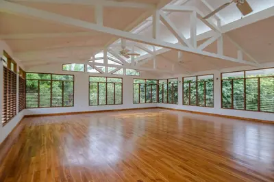 an empty room with wood floors and windows at Salvatierra Beachfront Hotel in Puerto Coyote