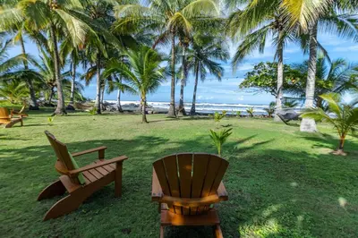 two chairs sitting on the grass near the beach at Salvatierra Beachfront Hotel in Puerto Coyote