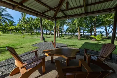 a patio with chairs and a table and trees at Salvatierra Beachfront Hotel in Puerto Coyote