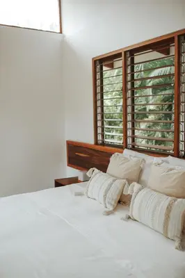 a white bed with white pillows and a window at Salvatierra Beachfront Hotel in Puerto Coyote