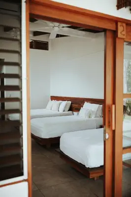 two beds in a room with a door open at Salvatierra Beachfront Hotel in Puerto Coyote