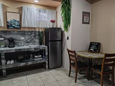 a kitchen with a table and a stainless steel refrigerator at Arenal Memories. in Fortuna