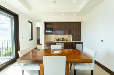 a dining room with a wooden table and white chairs at 360 Splendor 104B-Ocean View Condo-Breakfast in Playa Flamingo