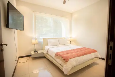a bedroom with a bed with a television and a window at CasaGuana in Playa Hermosa