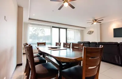 a dining room with a table and chairs and a couch at CasaGuana in Playa Hermosa