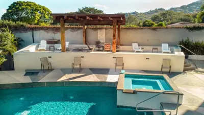 a swimming pool with a table and chairs next to a house at CasaGuana in Playa Hermosa