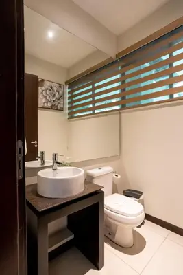 a bathroom with a white toilet and a sink at CasaGuana in Playa Hermosa