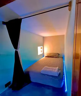 a bedroom with a bed in a room with blue lights at Shipwrecked Hostel in Uvita