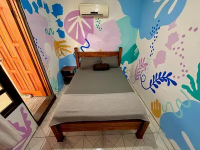 a bedroom with a bed with a colorful wall at Shipwrecked Hostel in Uvita
