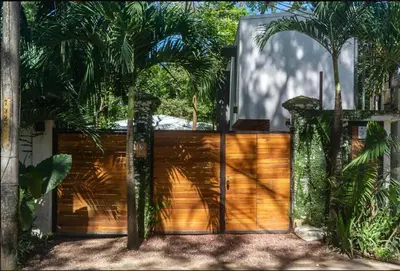 a wooden gate in front of a house with palm trees at Condo VNV walking distance to the beach in Nosara