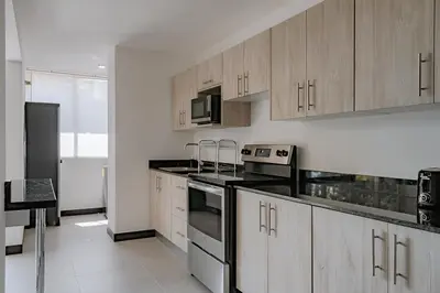 a kitchen with wooden cabinets and a black refrigerator at Departamento de lujo en la playa in Jacó