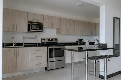 a kitchen with wooden cabinets and a counter top at Departamento de lujo en la playa in Jacó