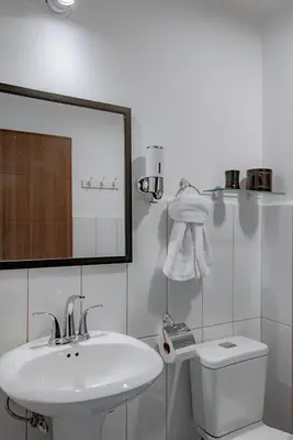 a white bathroom with a sink and a toilet at Departamento de lujo en la playa in Jacó
