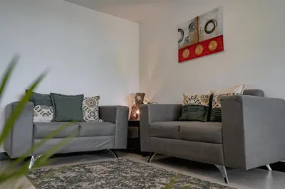 a living room with two chairs and a couch at Departamento de lujo en la playa in Jacó