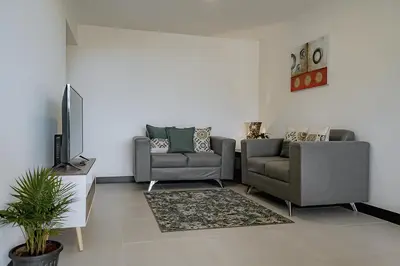 a living room with two couches and a television at Departamento de lujo en la playa in Jacó