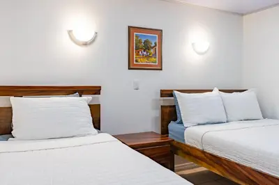 two beds in a room with white walls at Laguna Eco Village #205 Pool/ Tennis Courts/ BBQ in Quepos