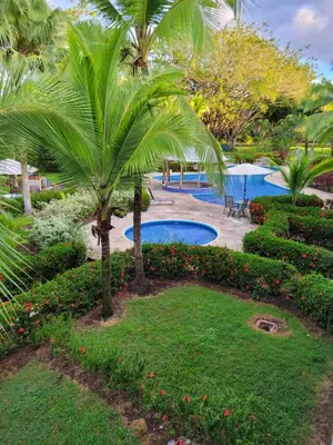 a resort with a pool and palm trees and bushes at Laguna Eco Village #205 Pool/ Tennis Courts/ BBQ in Quepos