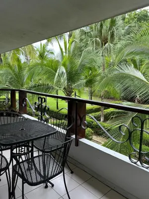 a balcony with a table and chairs and palm trees at Laguna Eco Village #205 Pool/ Tennis Courts/ BBQ in Quepos