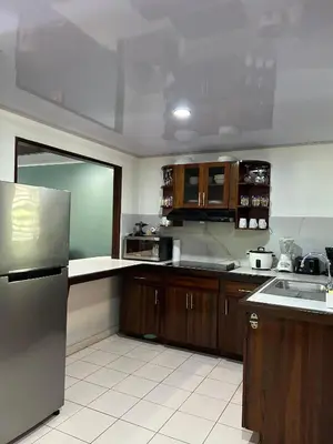 a kitchen with wooden cabinets and a stainless steel refrigerator at Laguna Eco Village #205 Pool/ Tennis Courts/ BBQ in Quepos