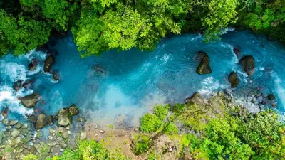 an aerial view of a river with rocks and blue water at Bitzu Dome-Bijagua Riverside Glamping in Bijagua