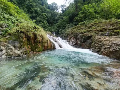 a waterfall in the middle of a river at Bitzu Dome-Bijagua Riverside Glamping in Bijagua
