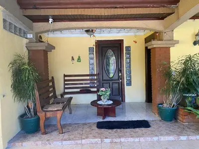 a porch with a bench and a wooden door at Casa Lupita Alajuela in Alajuela City